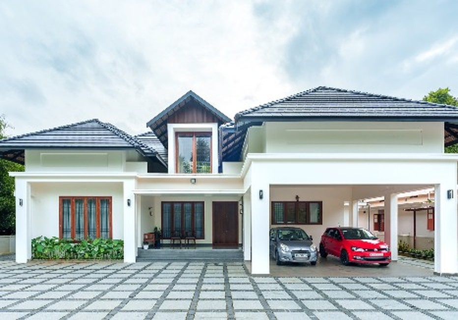 Symmetrical white home with dark tiled gable roofs and a wide paved forecourt